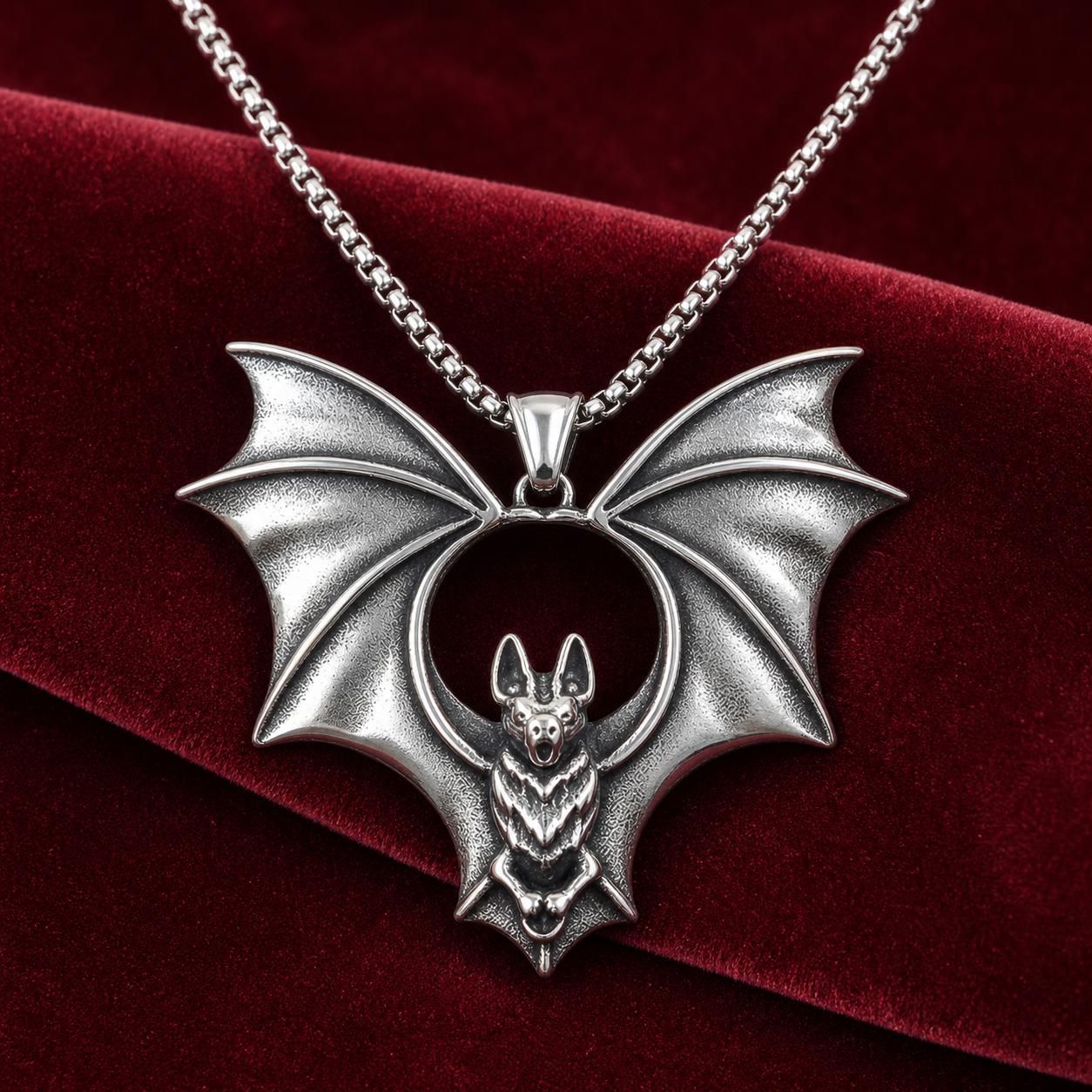 Silver flying bat pendant necklace styled on burgundy velvet