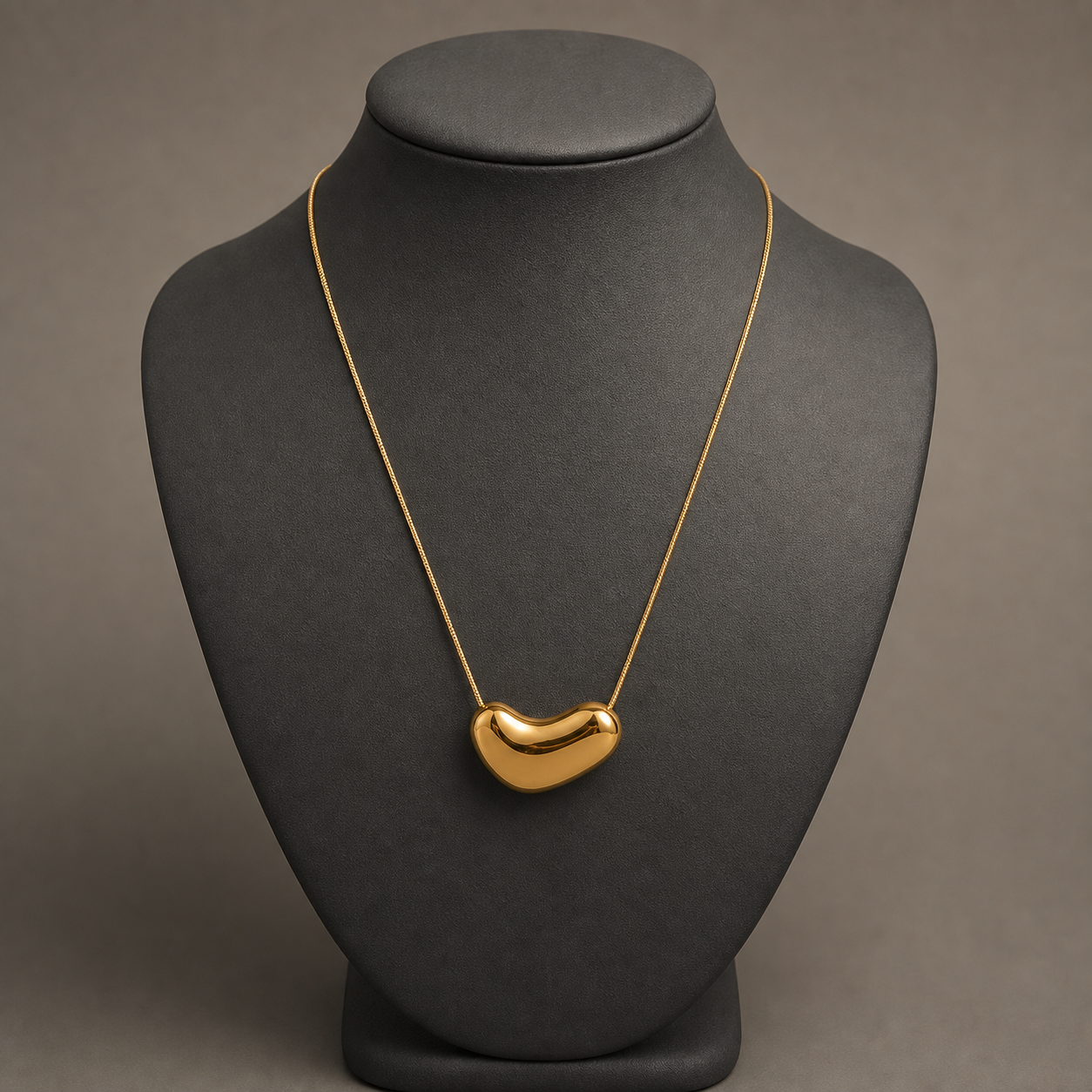 Gold irregular oval pendant on charcoal jewelry bust