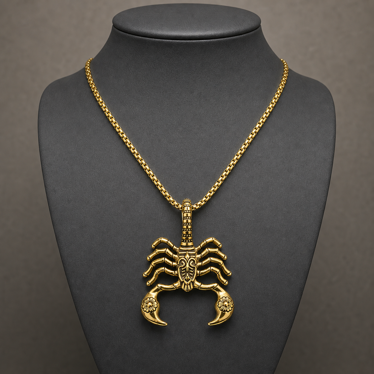 Gold gothic scorpion pendant necklace displayed on a charcoal jewelry bust