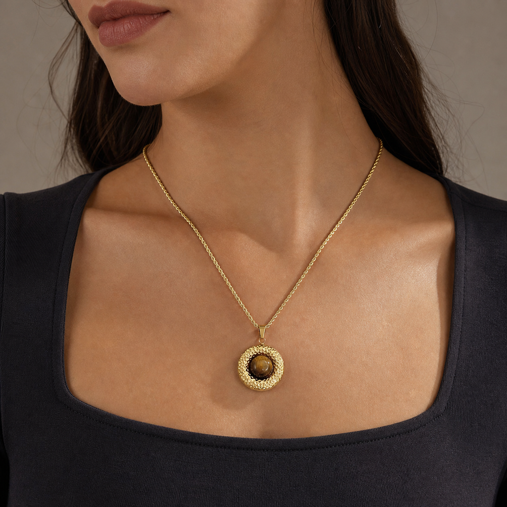 Hammered tiger-eye disc pendant necklace worn with a charcoal square-neck top