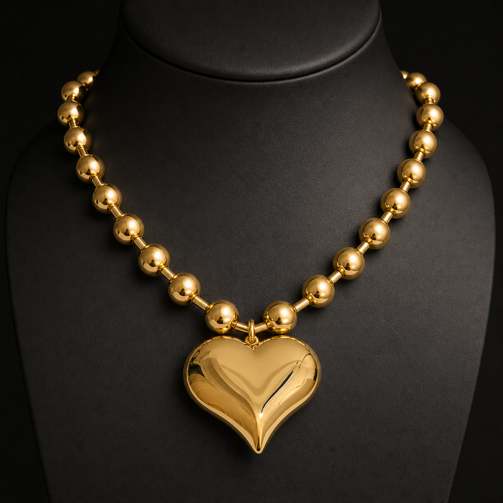 Polished gold heart and bead statement necklace on charcoal bust