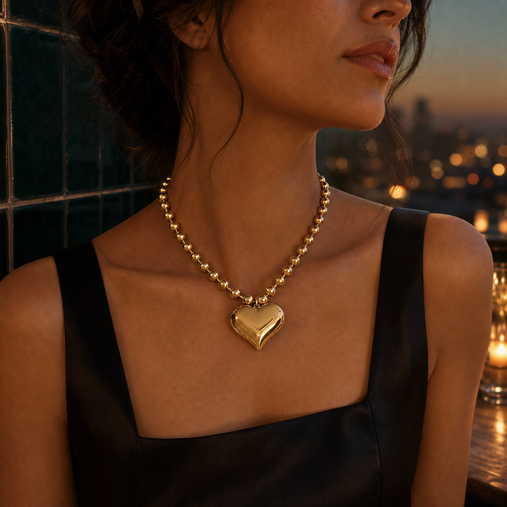 Polished gold heart and bead statement necklace worn at dusk