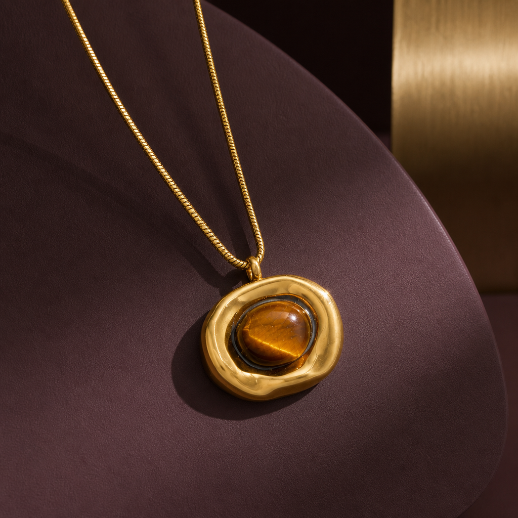 Irregular gold tiger-eye pendant necklace on an aubergine sculptural display