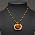 Irregular gold tiger-eye pendant necklace on charcoal jewelry bust