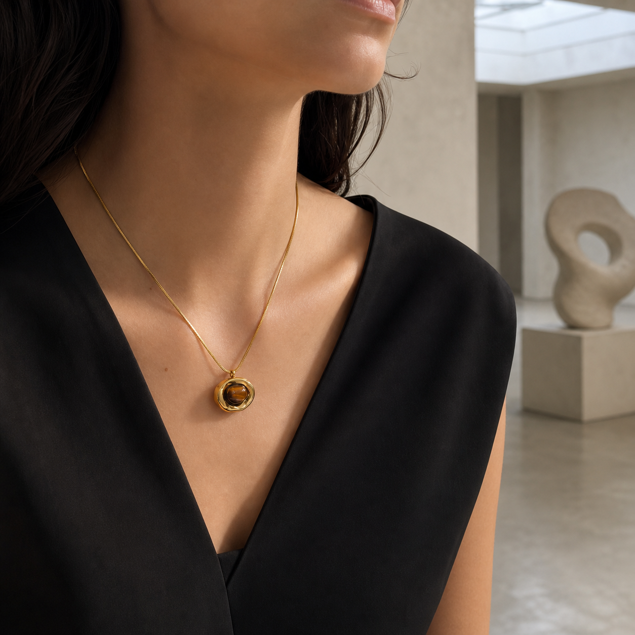 Irregular gold tiger-eye pendant necklace worn in a contemporary museum