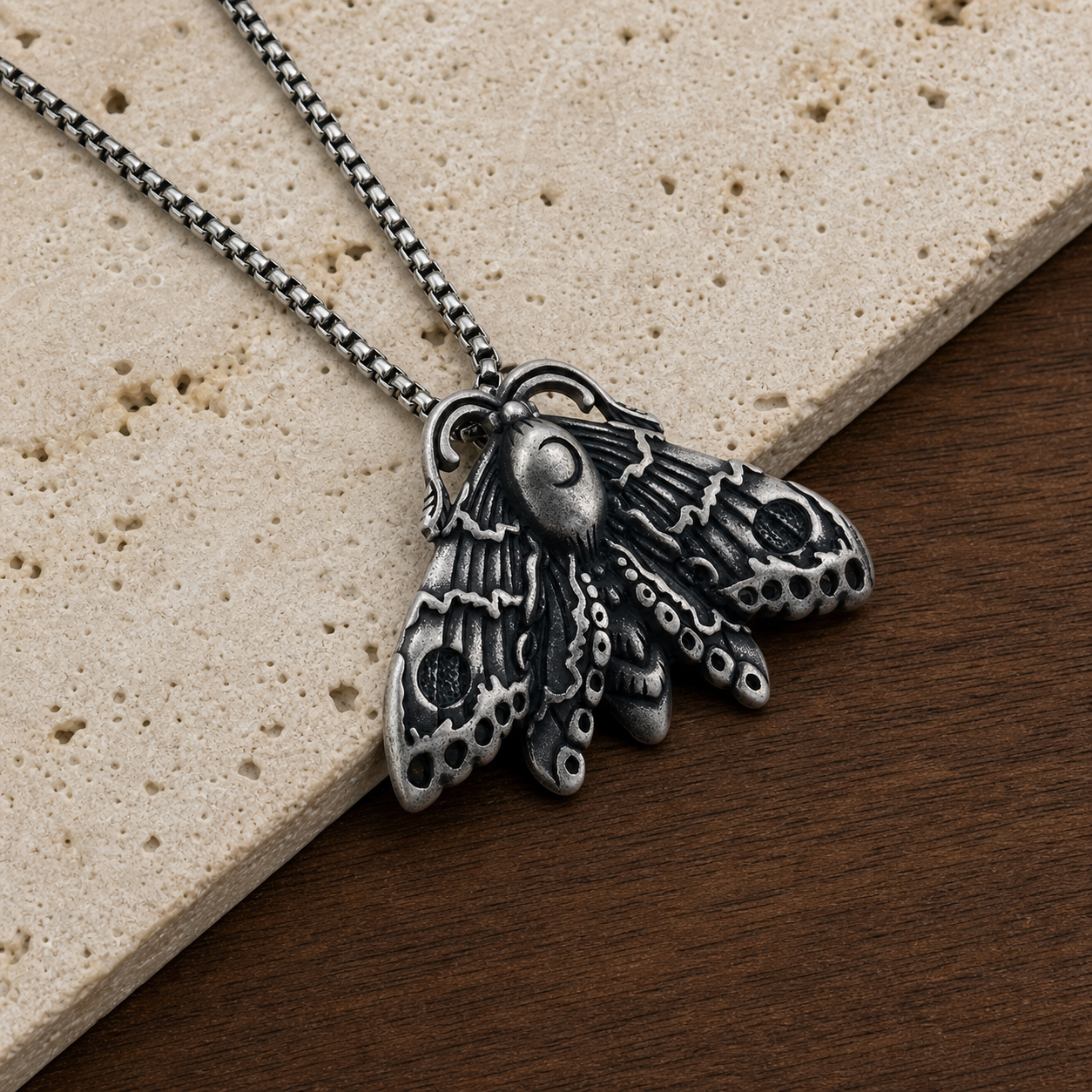 Gothic moon moth pendant necklace styled on travertine and walnut