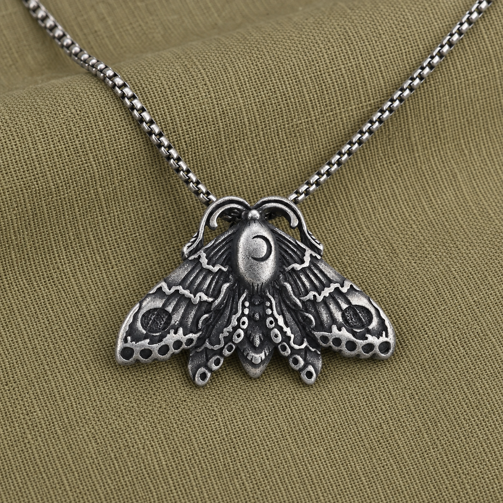 Gothic moon moth pendant necklace styled on olive linen