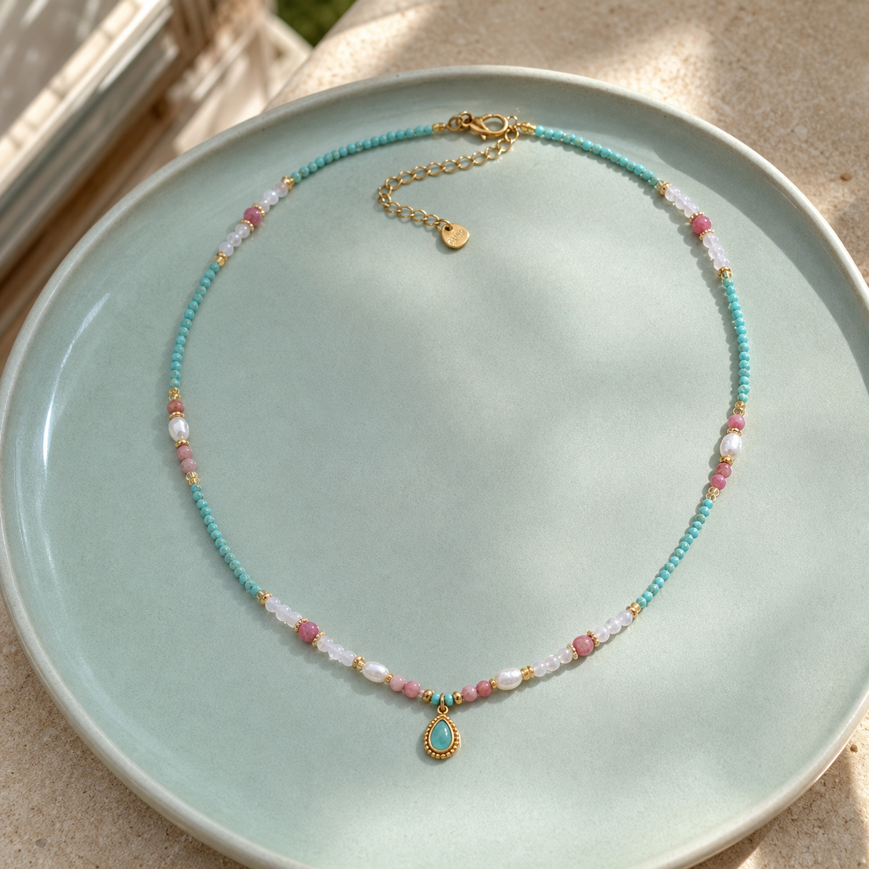 Natural-stone pearl waterdrop necklace on a pale-aqua ceramic tray