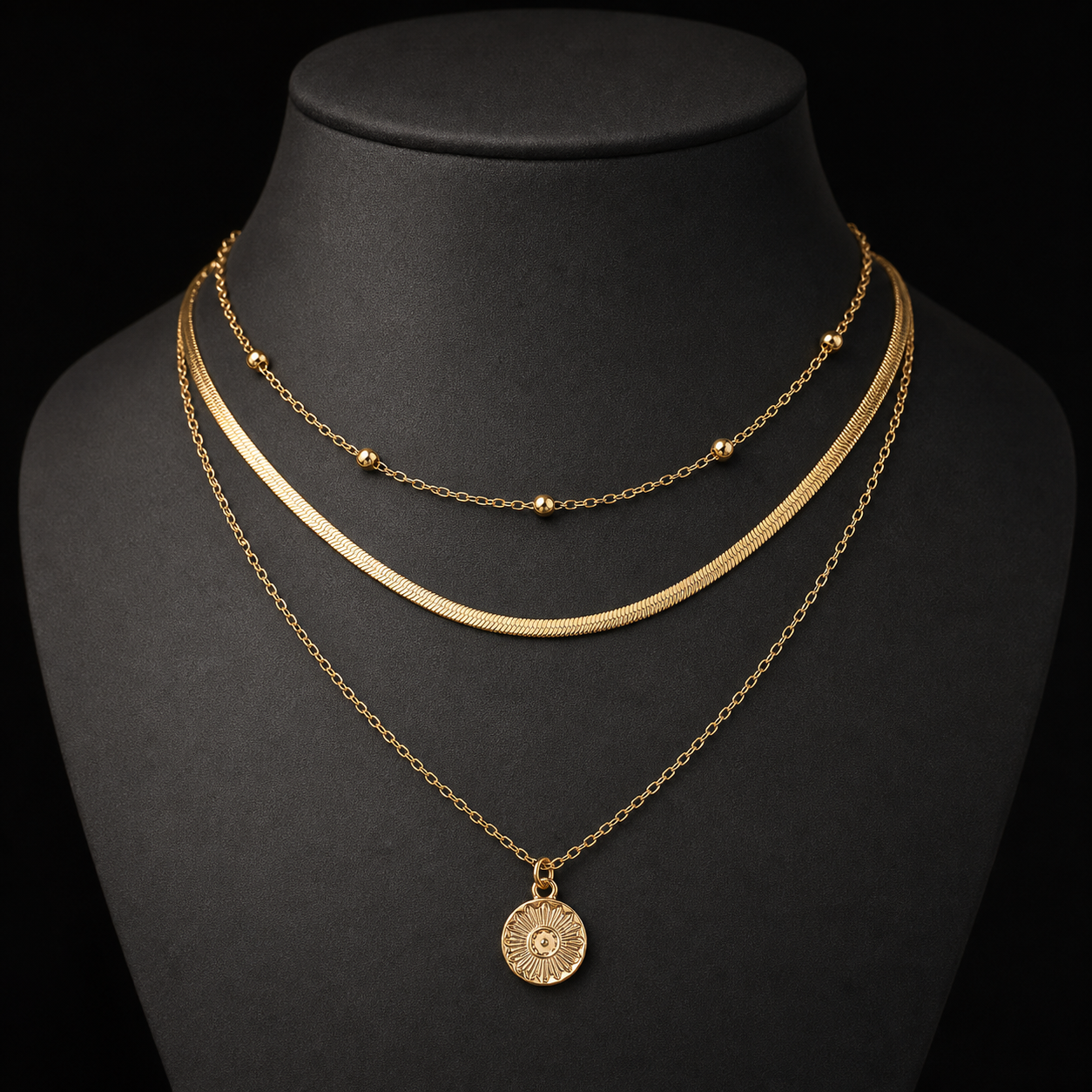 Gold three-layer round pendant necklace on charcoal bust